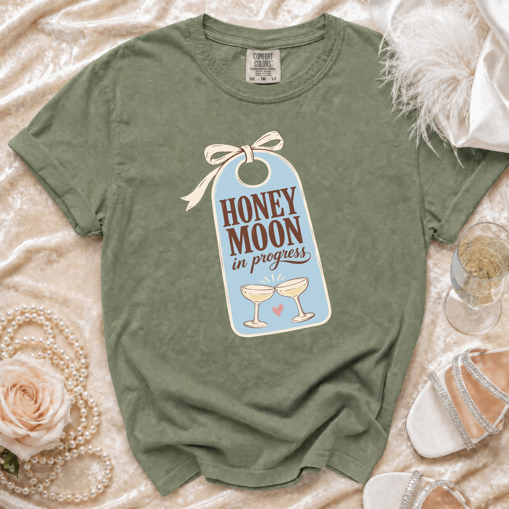 Green t-shirt with "Honeymoon in Progress" text and champagne glasses graphic.