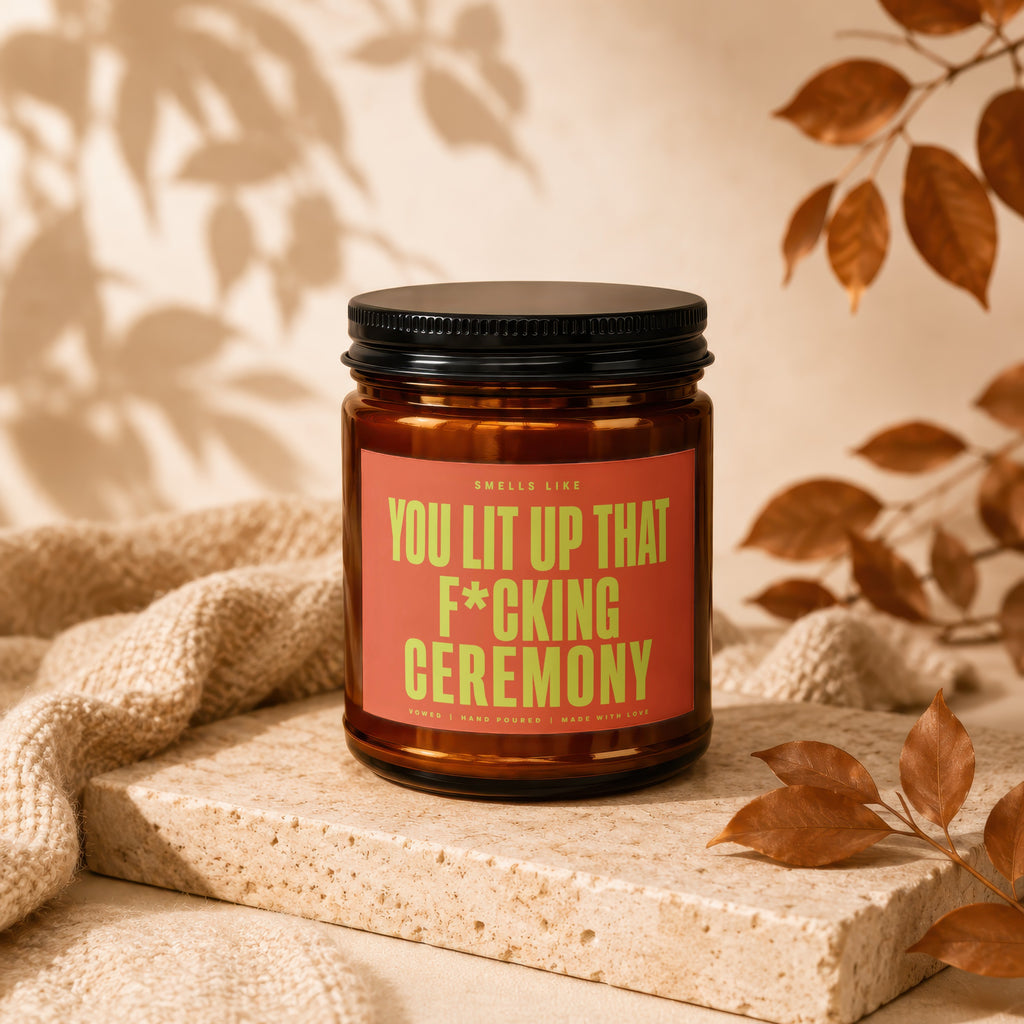 Amber candle with a red label reading "Smells like you lit up that f*cking ceremony."