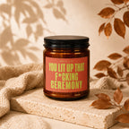 Amber candle with a red label reading "Smells like you lit up that f*cking ceremony."