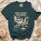 T-shirt with "Here Comes The Bride" text and illustration of bride riding dragon.