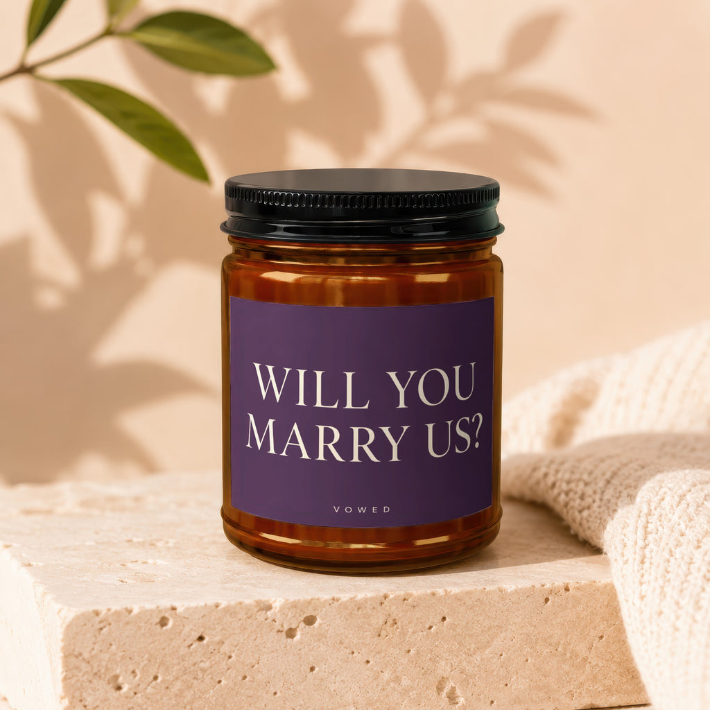Amber candle in a jar with a black lid, features "WILL YOU MARRY US?" text.
