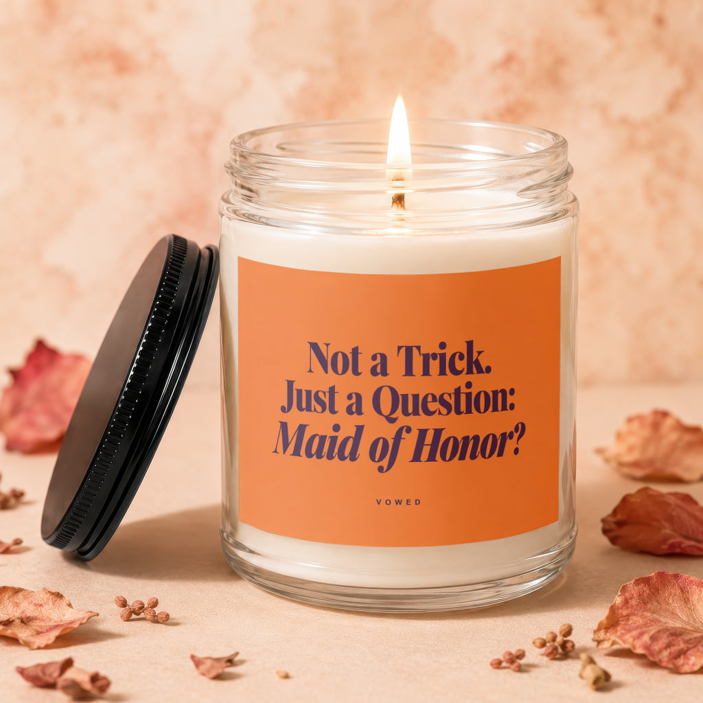 Candle with orange label reading "Not a Trick. Just a Question: Maid of Honor?"