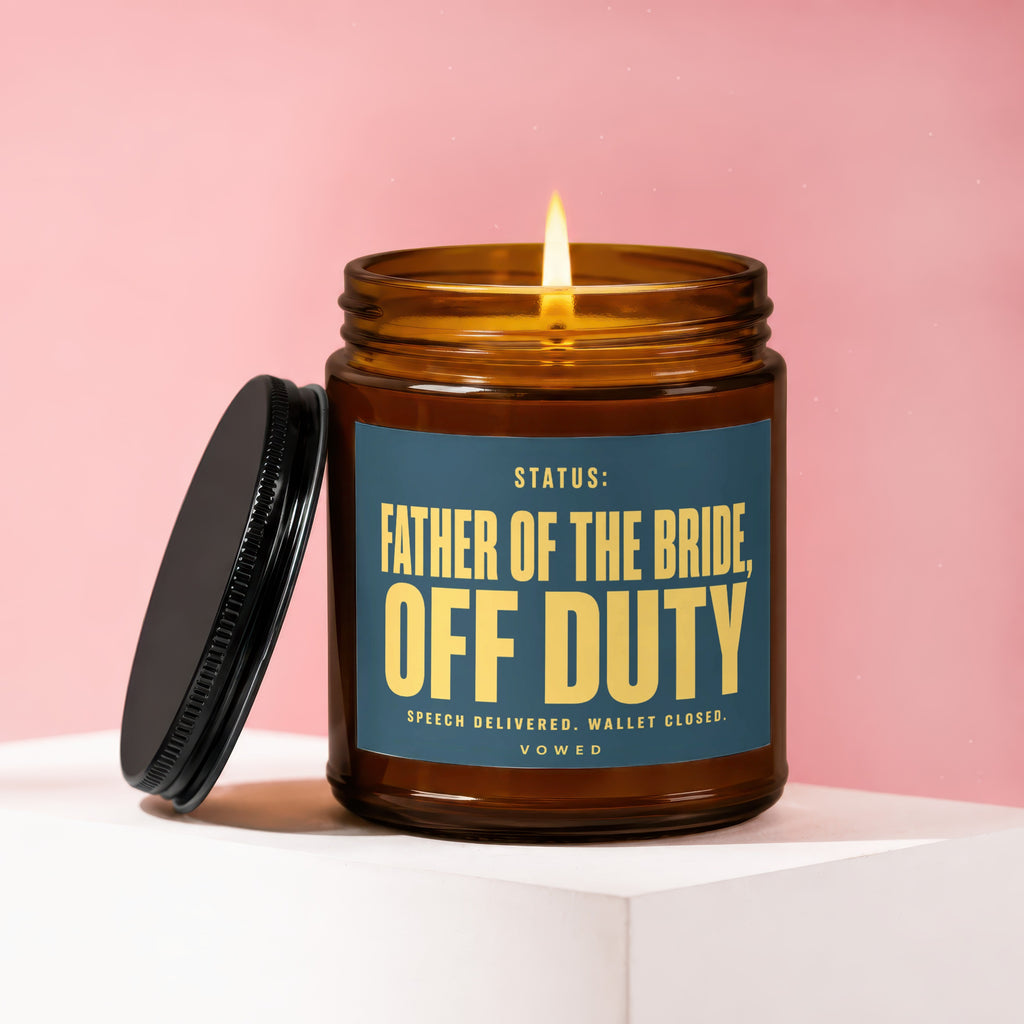 Lit candle in amber glass jar with "FATHER OF THE BRIDE, OFF DUTY" label.