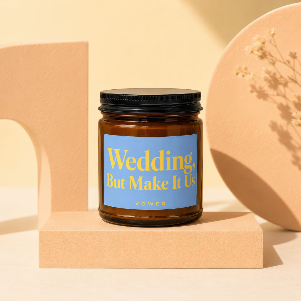Amber glass candle with blue label reading "Wedding, But Make It Us".