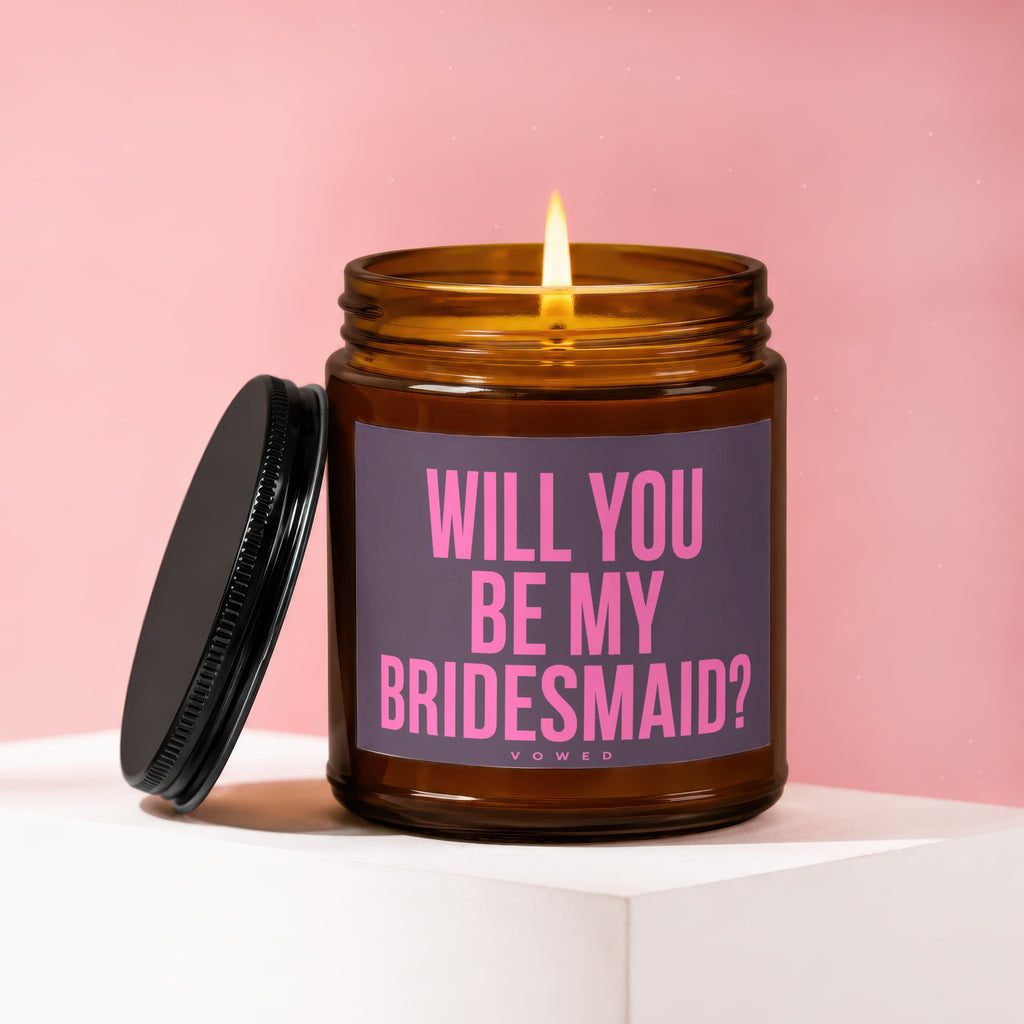 Candle with a lit wick and lid, labeled "Will You Be My Bridesmaid?"