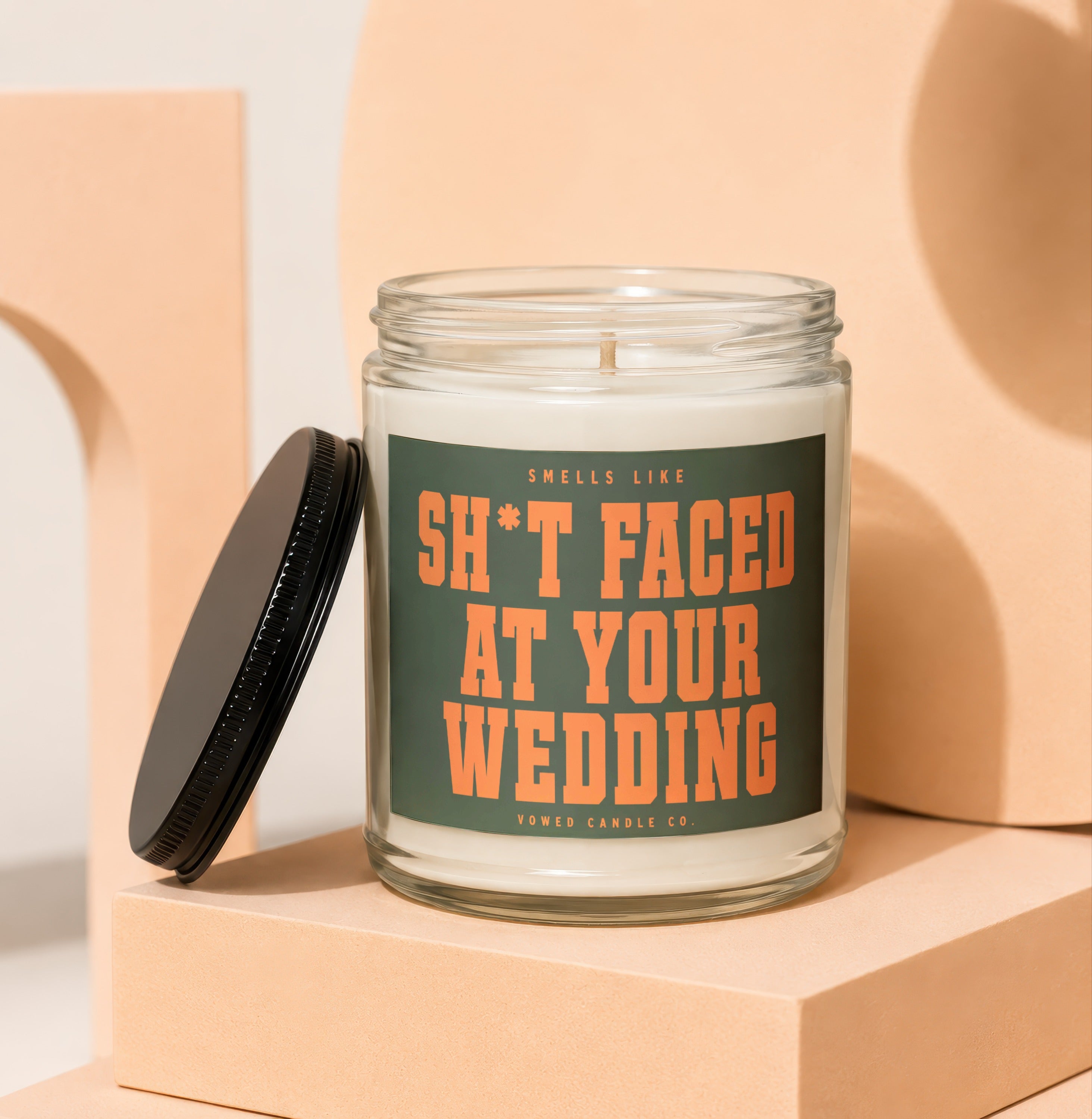 Candle with lid off, showing "Smells like sh*t faced at your wedding" text.