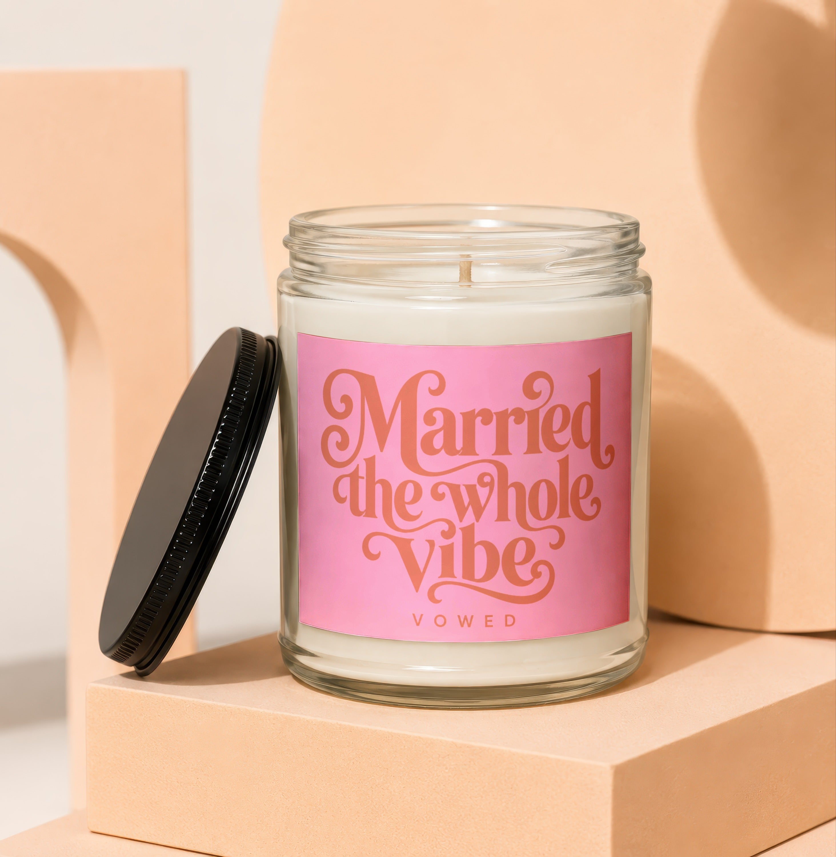 Glass candle with pink label that reads "Married the whole Vibe" [VOWED]