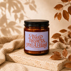 Amber jar candle with a lavender label that reads "Two Hearts, One U-Haul" and "VOWED".