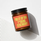 Brown glass candle with orange label: "You Lit Up That F*cking Ceremony."