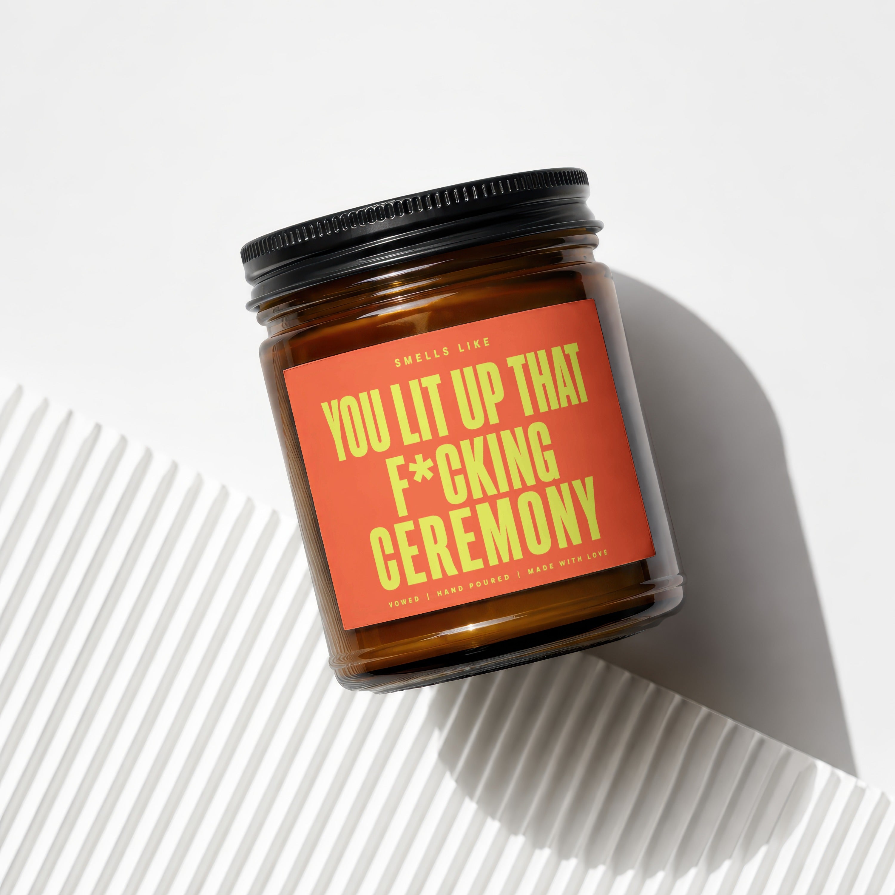 Brown glass candle with orange label: "You Lit Up That F*cking Ceremony."