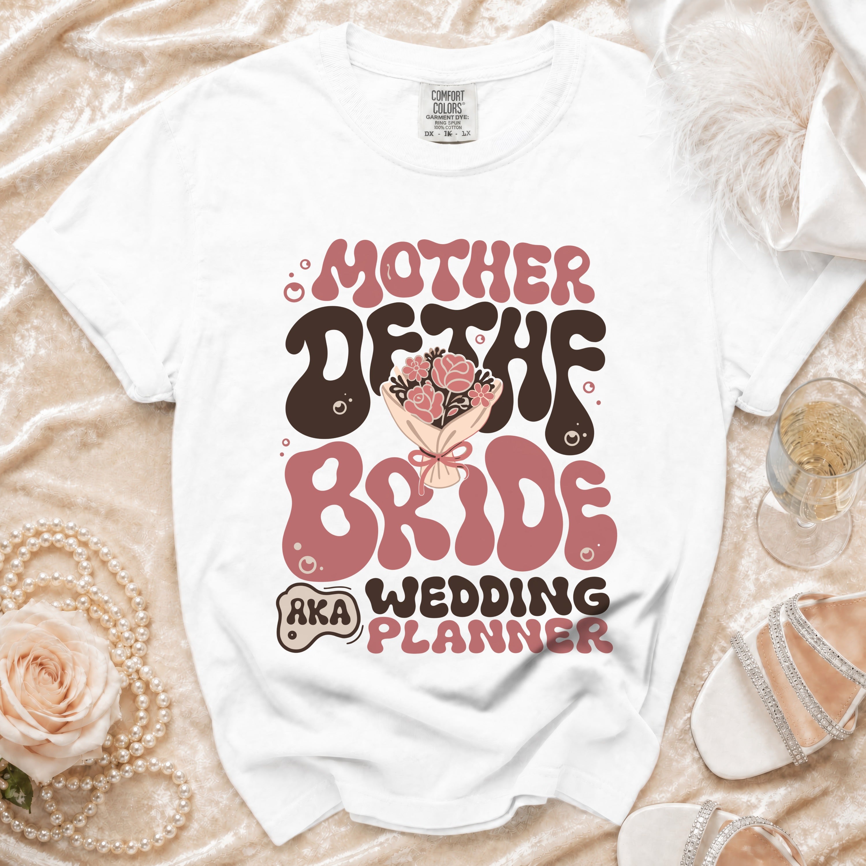 White t-shirt with "Mother of the Bride Wedding Planner" text in retro font.