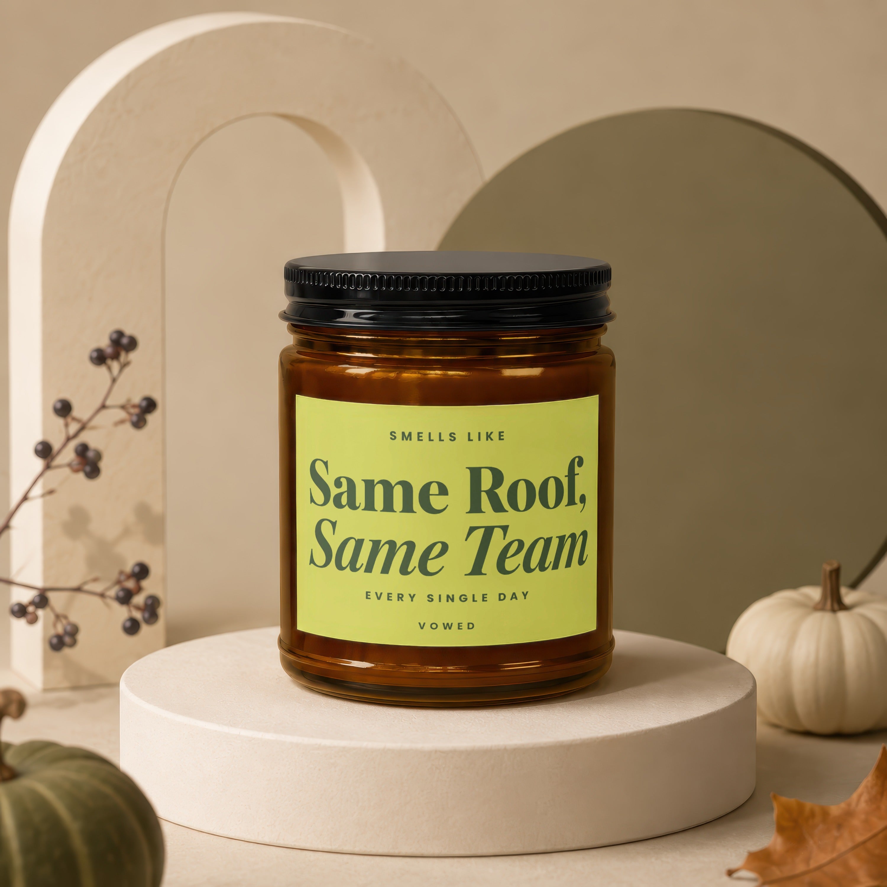 Amber candle in jar with black lid, green label reads "Same Roof, Same Team".