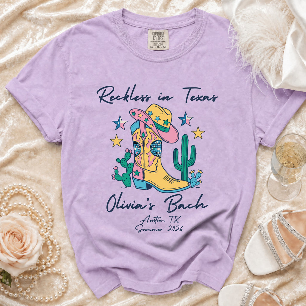 Purple t-shirt with "Reckless in Texas Olivia's Bach Austin, TX Summer 2026" and cowboy boot graphic.