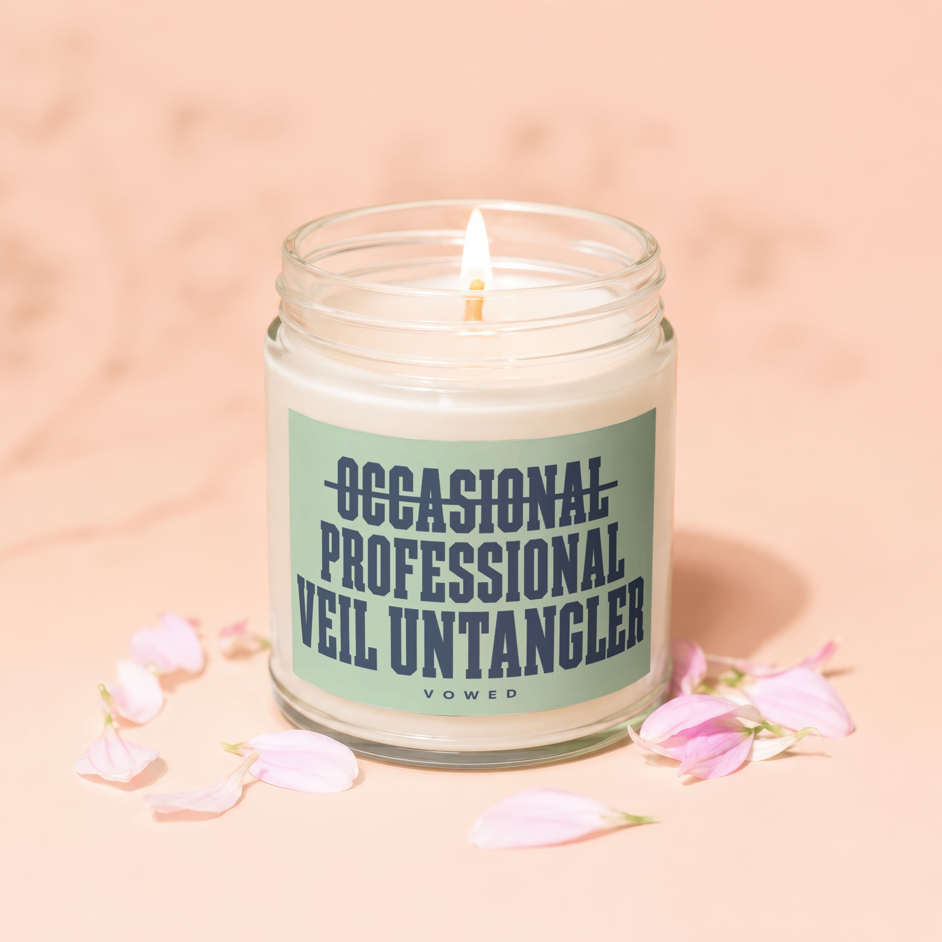 Lit candle in a jar with "Occasional Professional Veil Untangler" text and pink petals.