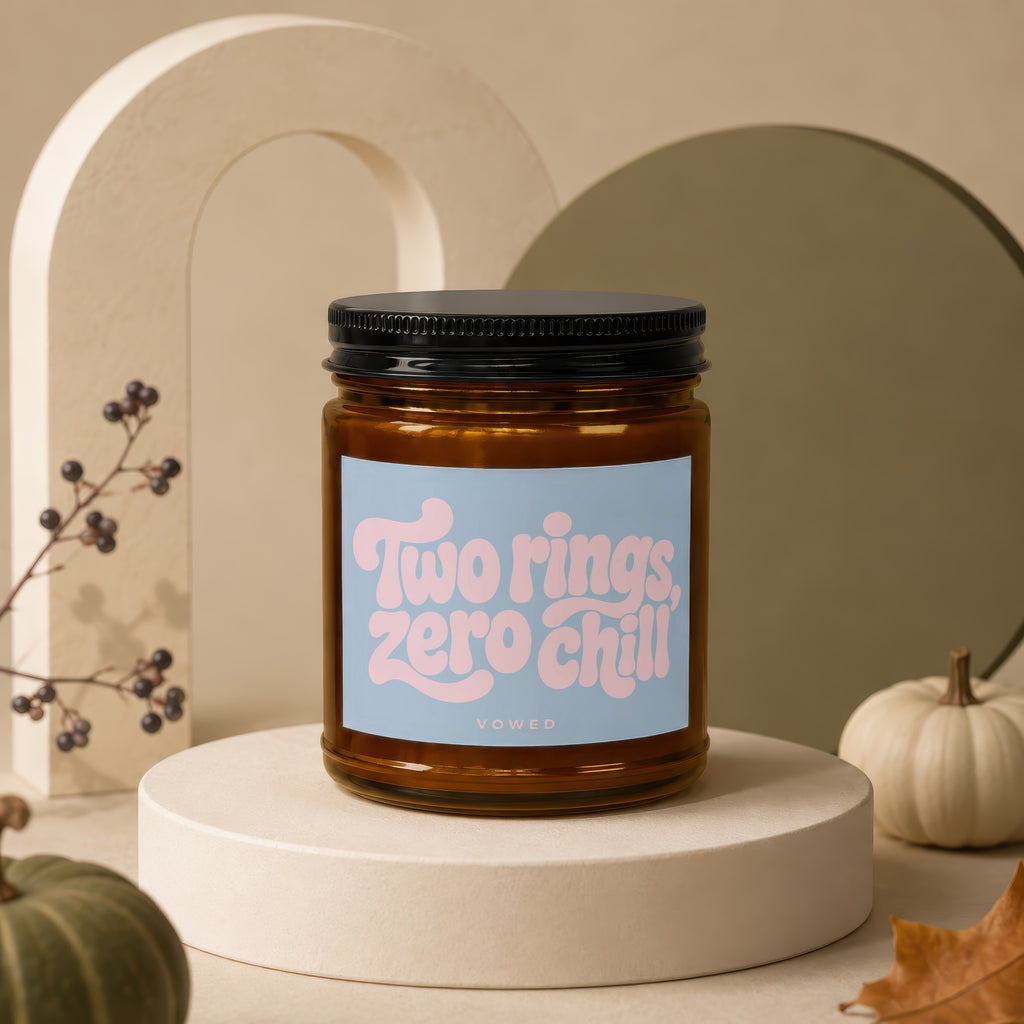 Amber jar candle with pink text "Two rings, zero chill" on a blue label.
