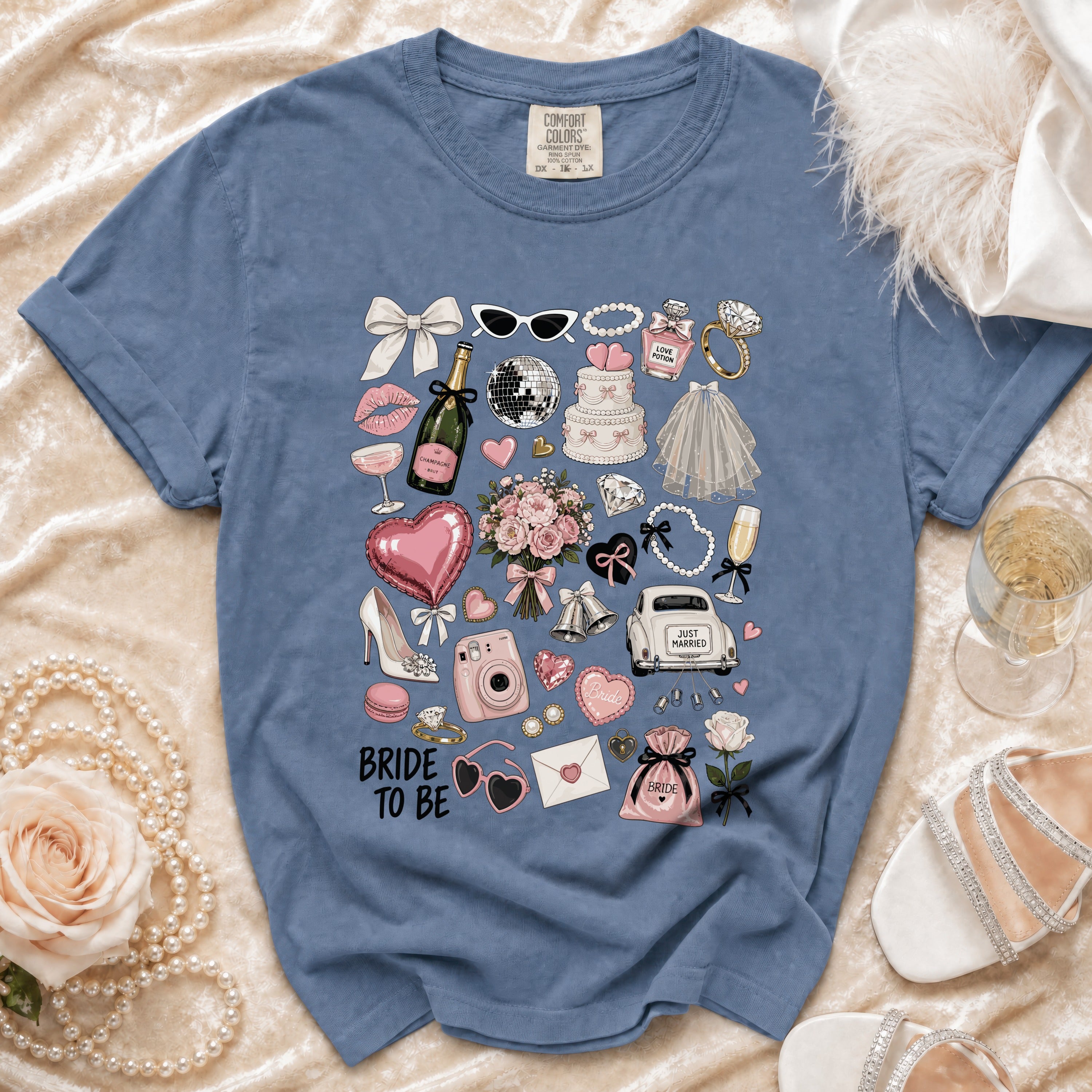 Blue t-shirt with "Bride to Be" and wedding icons including cake, champagne, and rings.