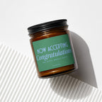 Jar candle with green label reading "NOW ACCEPTING Congratulations AND GIFTS. MOSTLY GIFTS. VOWED."