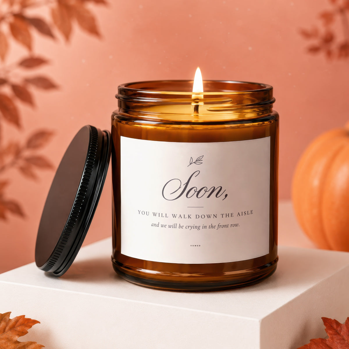 Amber glass candle with lit wick, featuring "Soon, You will walk down the aisle" text.