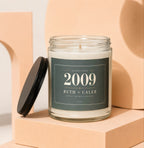 Glass candle with a dark green label reading "Established 2009 Ruth + Caleb Still Going Strong".