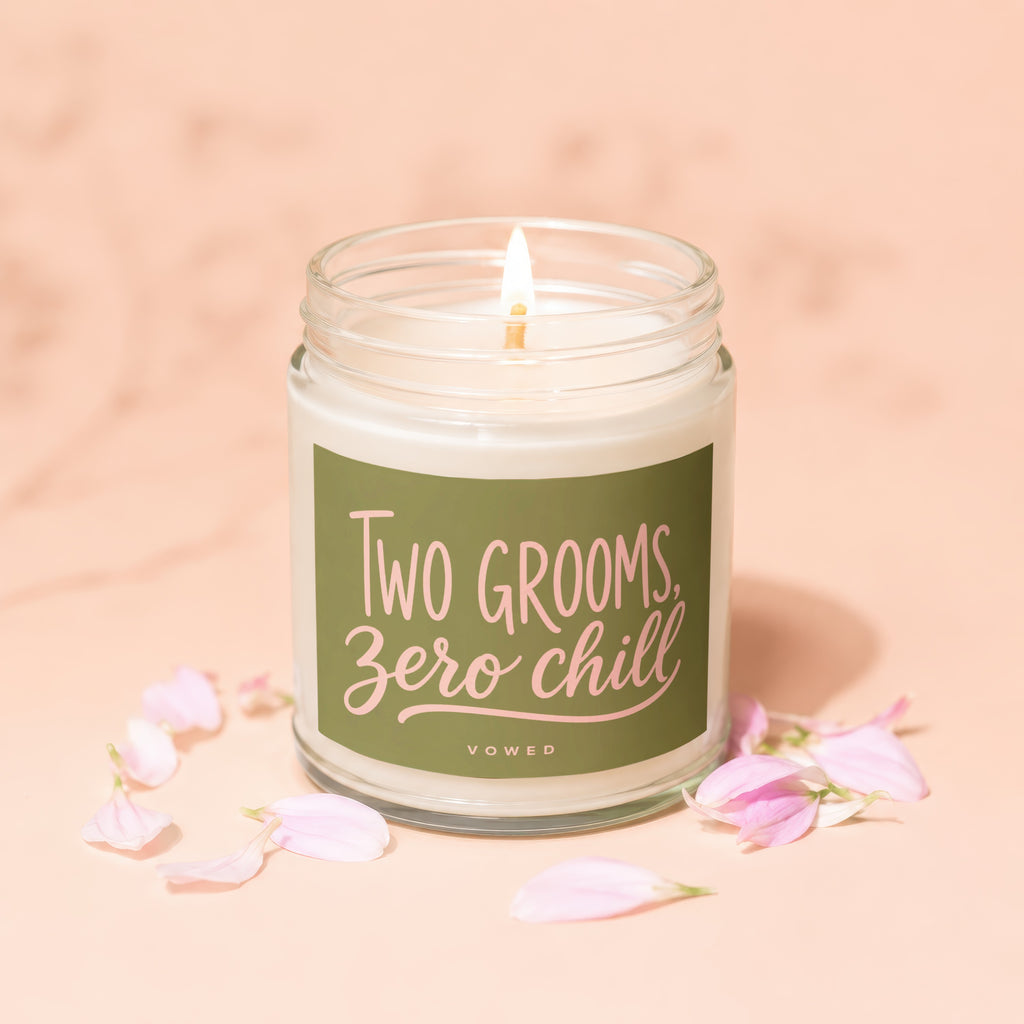 Candle with lit wick and green label reading "TWO GROOMS, Zero chill".