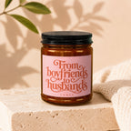 Amber jar candle with "From boyfriends to husbands" inscribed on a pink label.