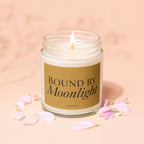 "Bound by Moonlight" candle with lit wick, surrounded by pink petals.