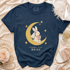 Navy t-shirt with a graphic of a bunny on a moon holding a heart, text reads "STARRY-EYED BRIDE".