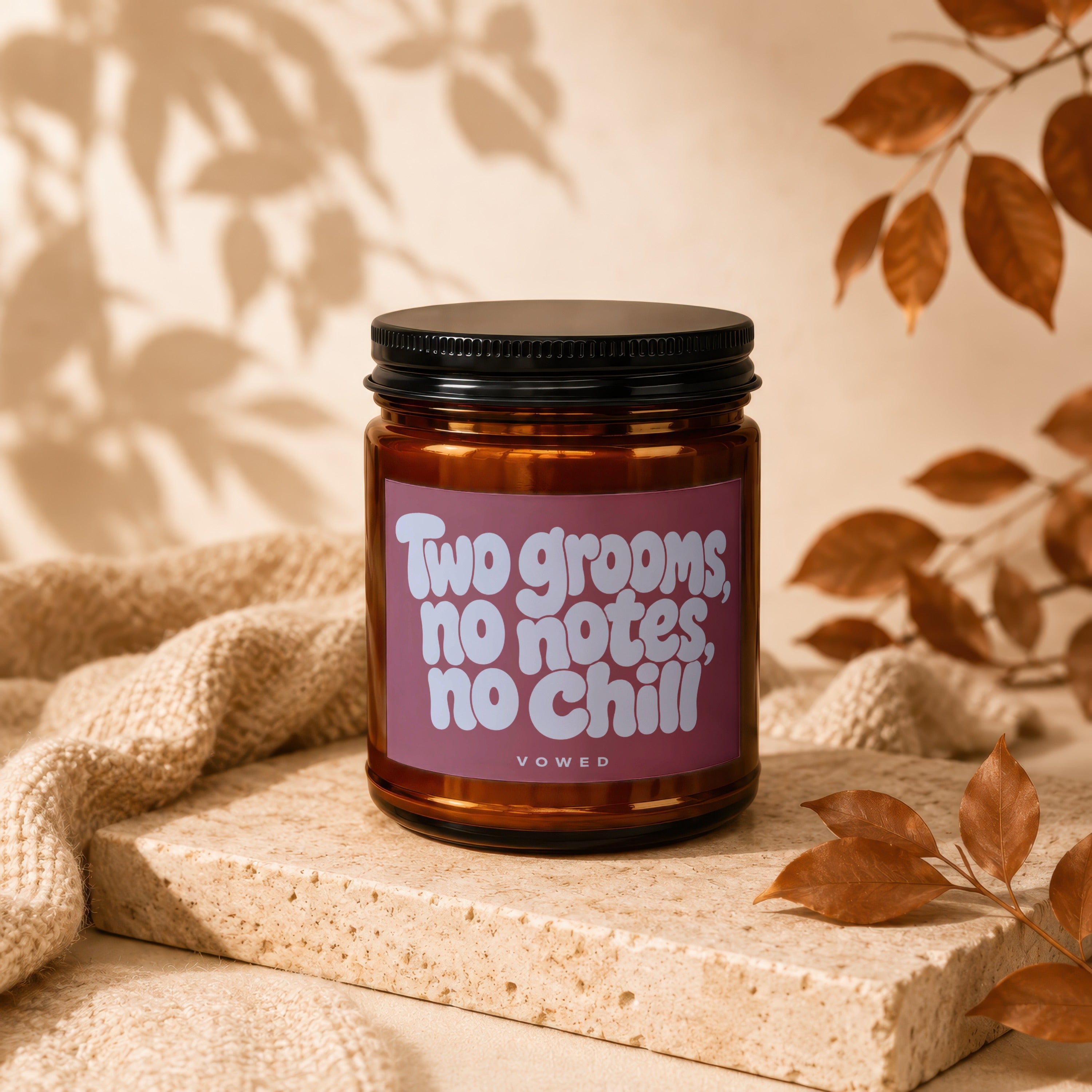 Brown candle with black lid and pink label reading "Two grooms, no notes, no chill."