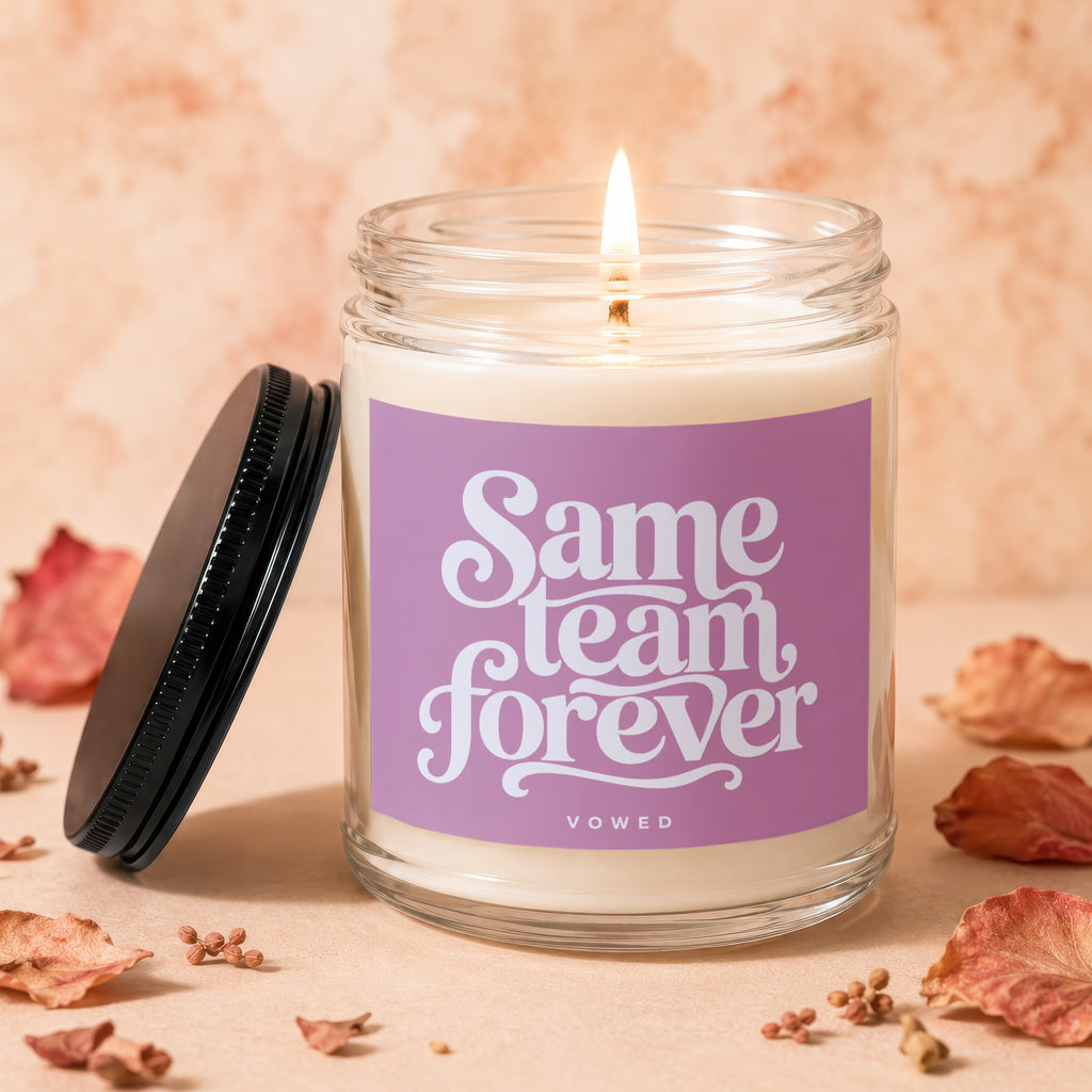Scented candle with purple label reading "Same Team Forever Vowed".
