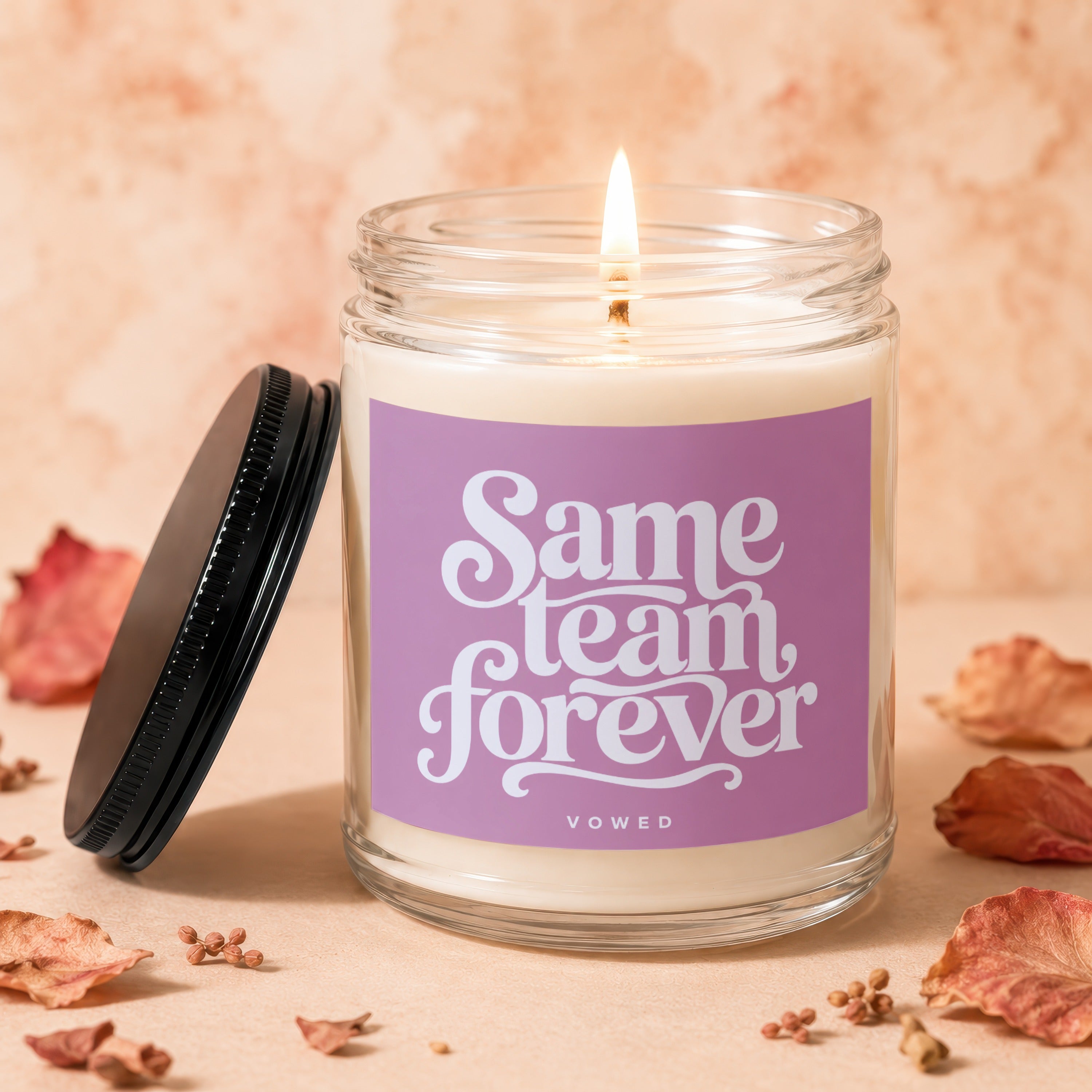 Scented candle with purple label reading "Same Team Forever Vowed".
