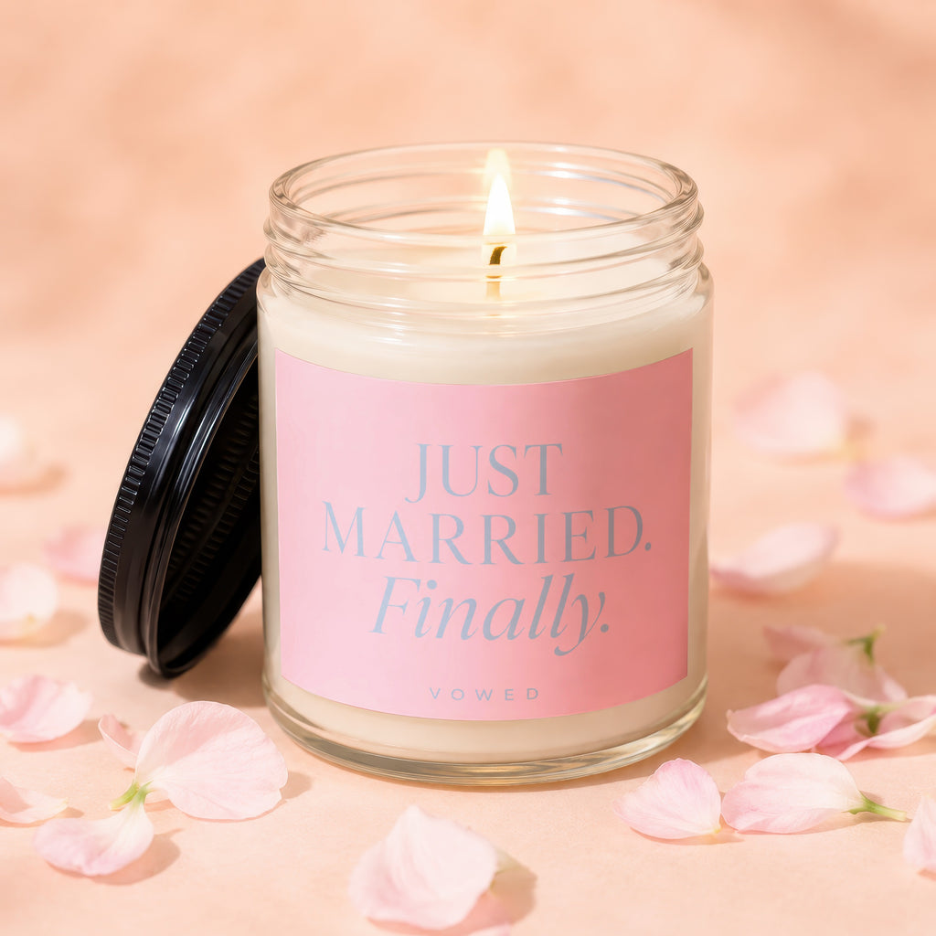 Candle with pink label reading "JUST MARRIED. Finally." surrounded by petals.