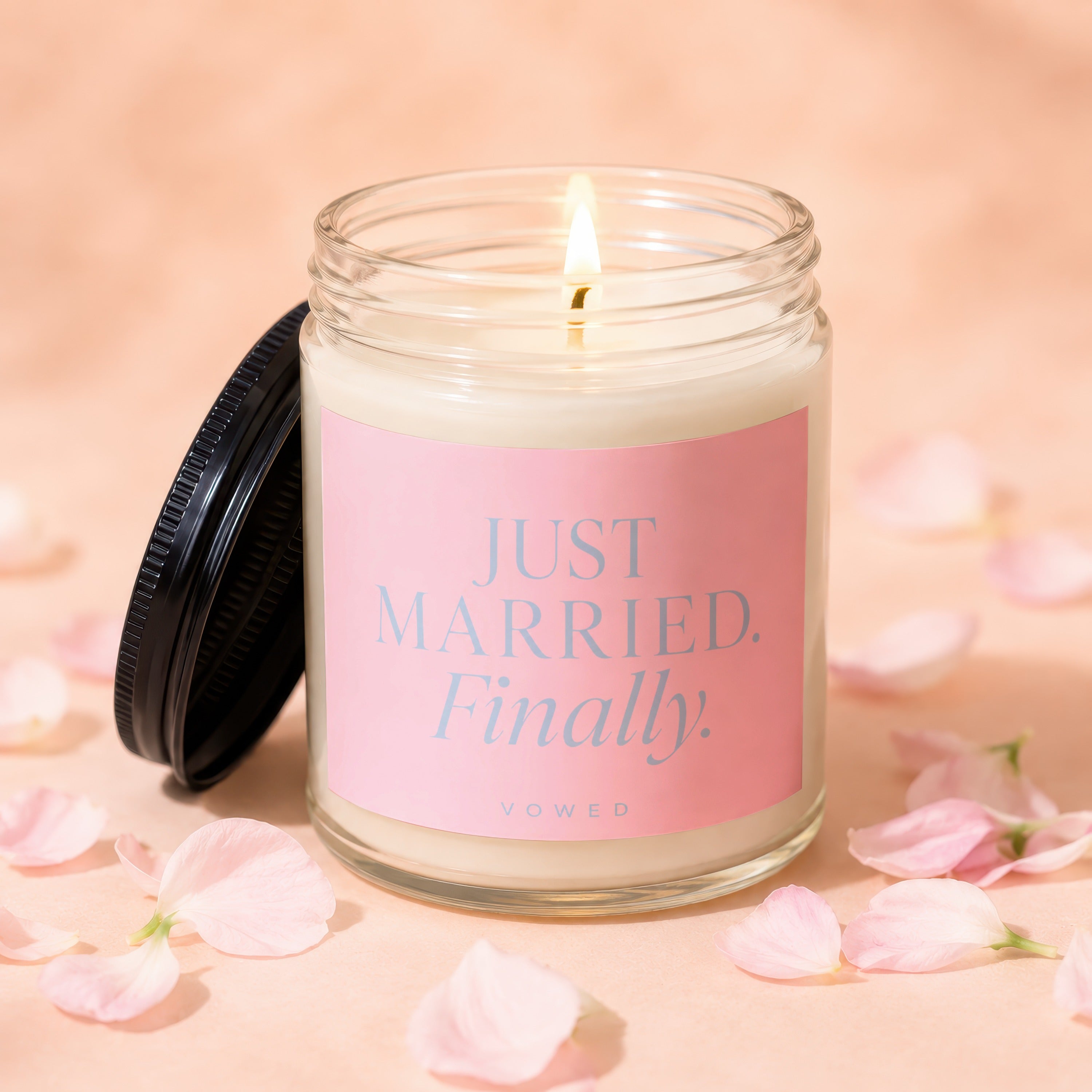 Candle with pink label reading "JUST MARRIED. Finally." surrounded by petals.
