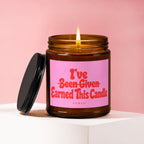 Amber glass candle with burning flame and pink label reading 'I've Been Given Earned This Candle'