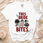 White t-shirt with "This Bride Bites" graphic featuring a bouquet, veil, ring, and fangs.