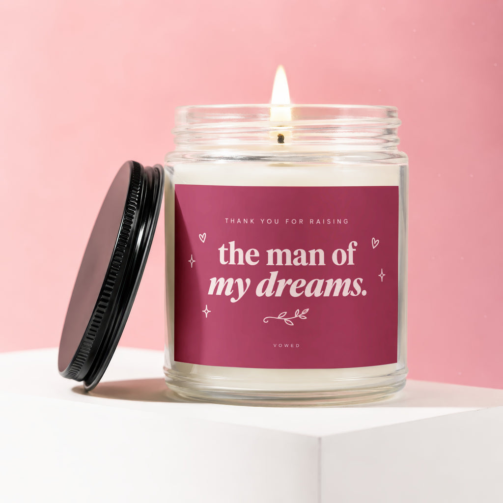 Candle with lit wick and pink label reading "Thank You For Raising The Man Of My Dreams."