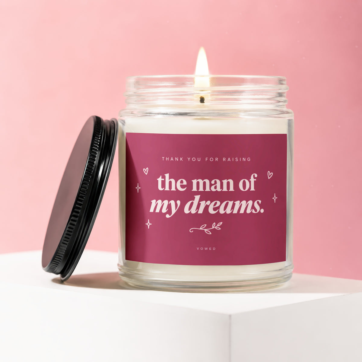 Candle with lit wick and pink label reading "Thank You For Raising The Man Of My Dreams."