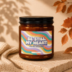 Amber glass candle with colorful wavy label that reads "BE STILL, MY HEART! YOU'RE ENGAGED!"