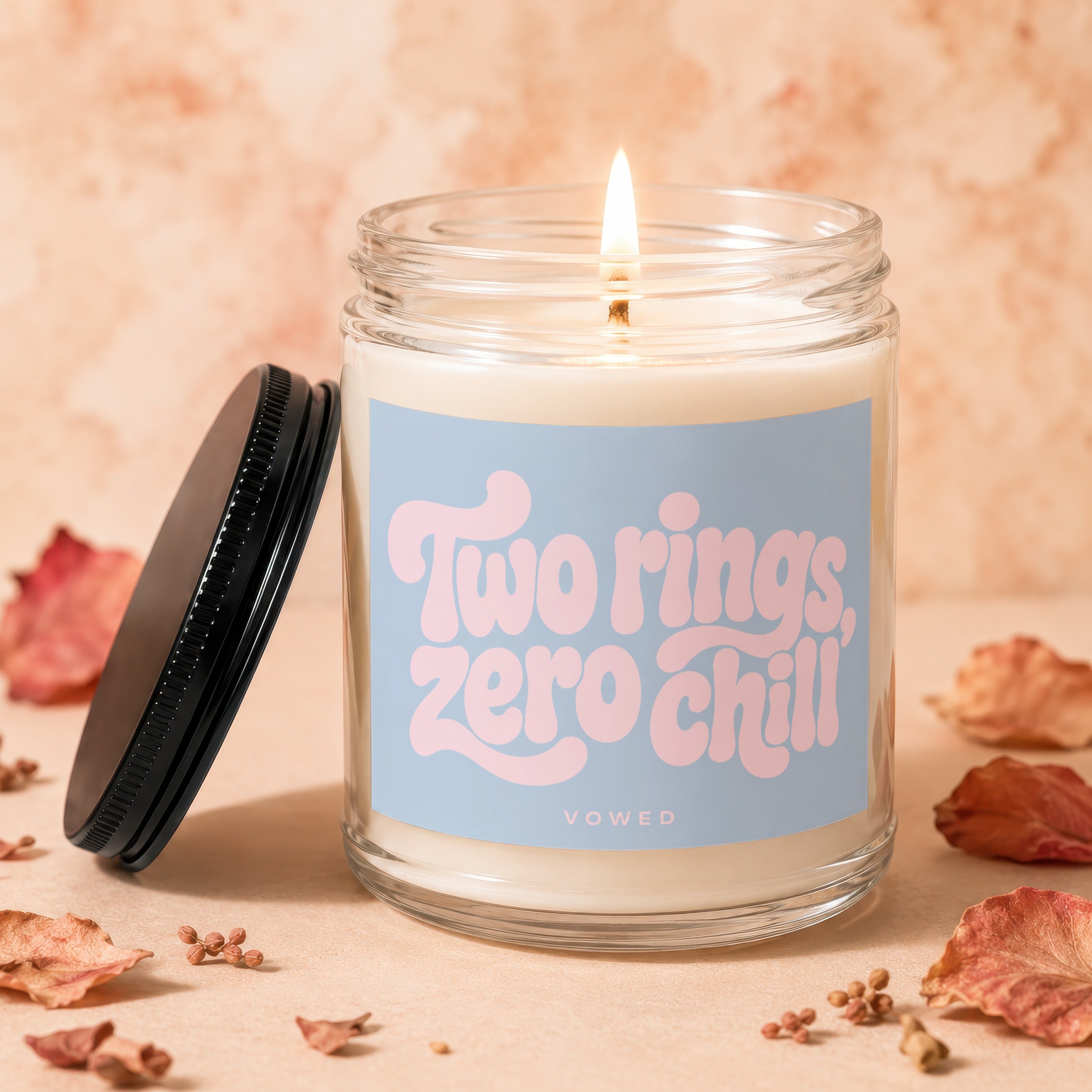Candle lit, with a blue label reading "Two rings, zero chill" and "VOWED".