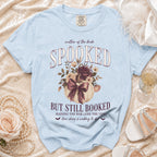 Light blue shirt with "Mother of the Bride Spooked But Still Booked" text and floral pumpkin graphic.