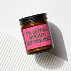 Brown candle in a jar with a pink label that reads "I'M GETTING HITCHED. GET OVER HERE."