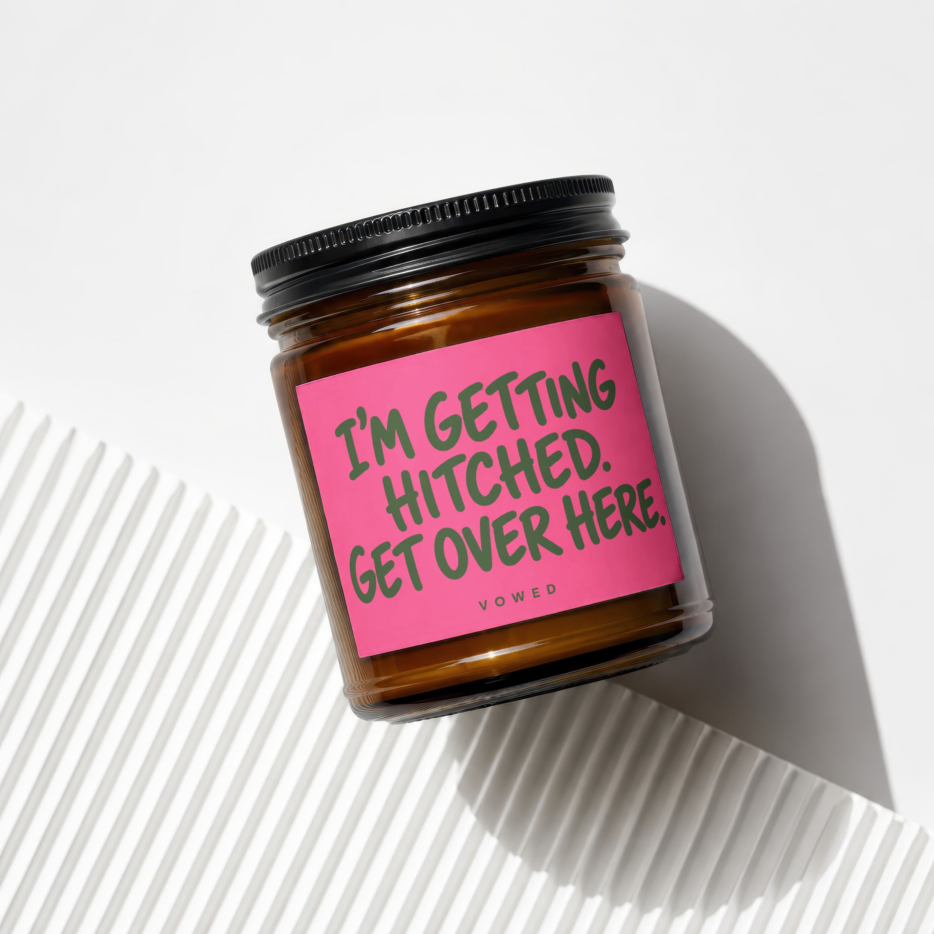 Brown candle in a jar with a pink label that reads "I'M GETTING HITCHED. GET OVER HERE."