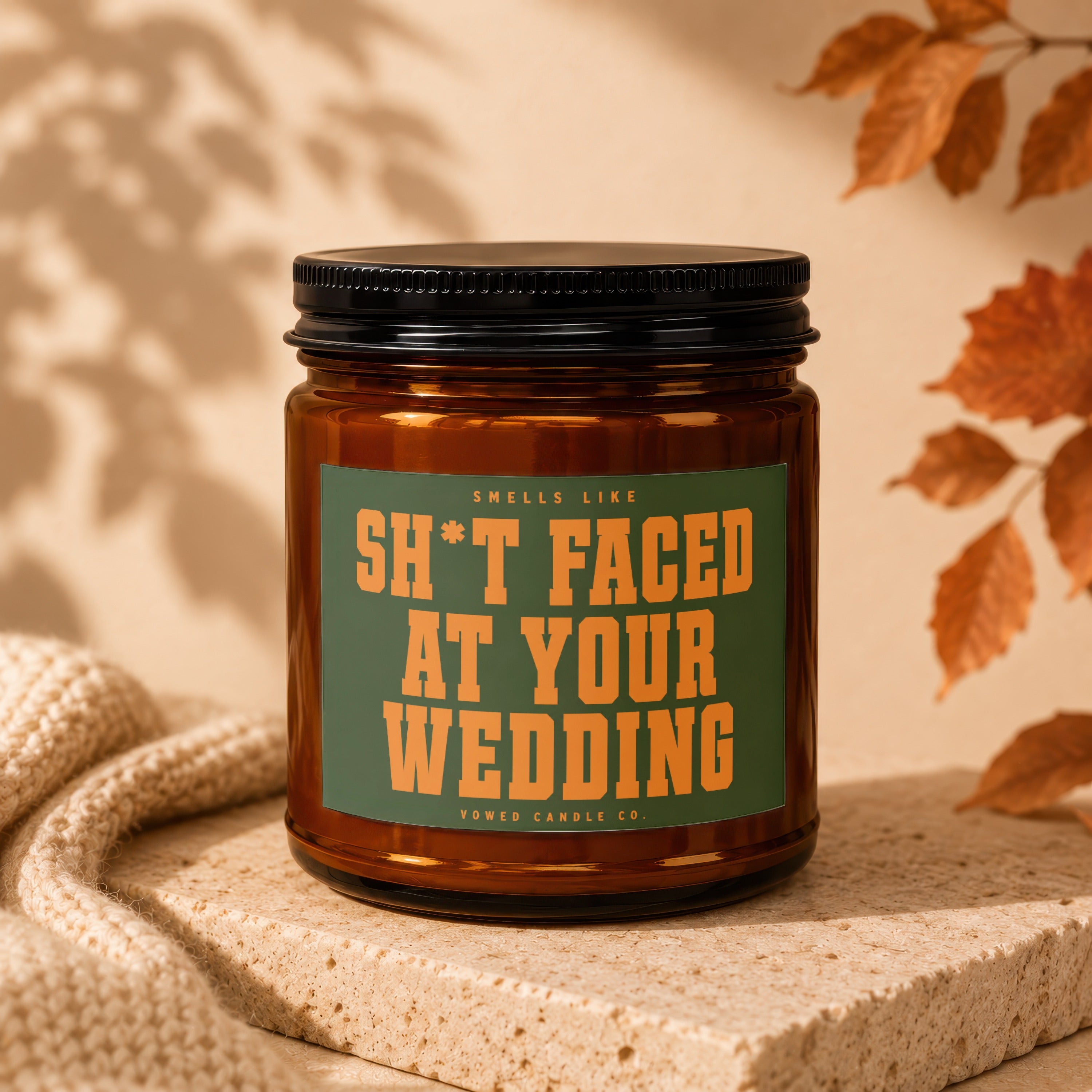Amber candle with black lid labeled "Smells Like S*** Faced At Your Wedding".