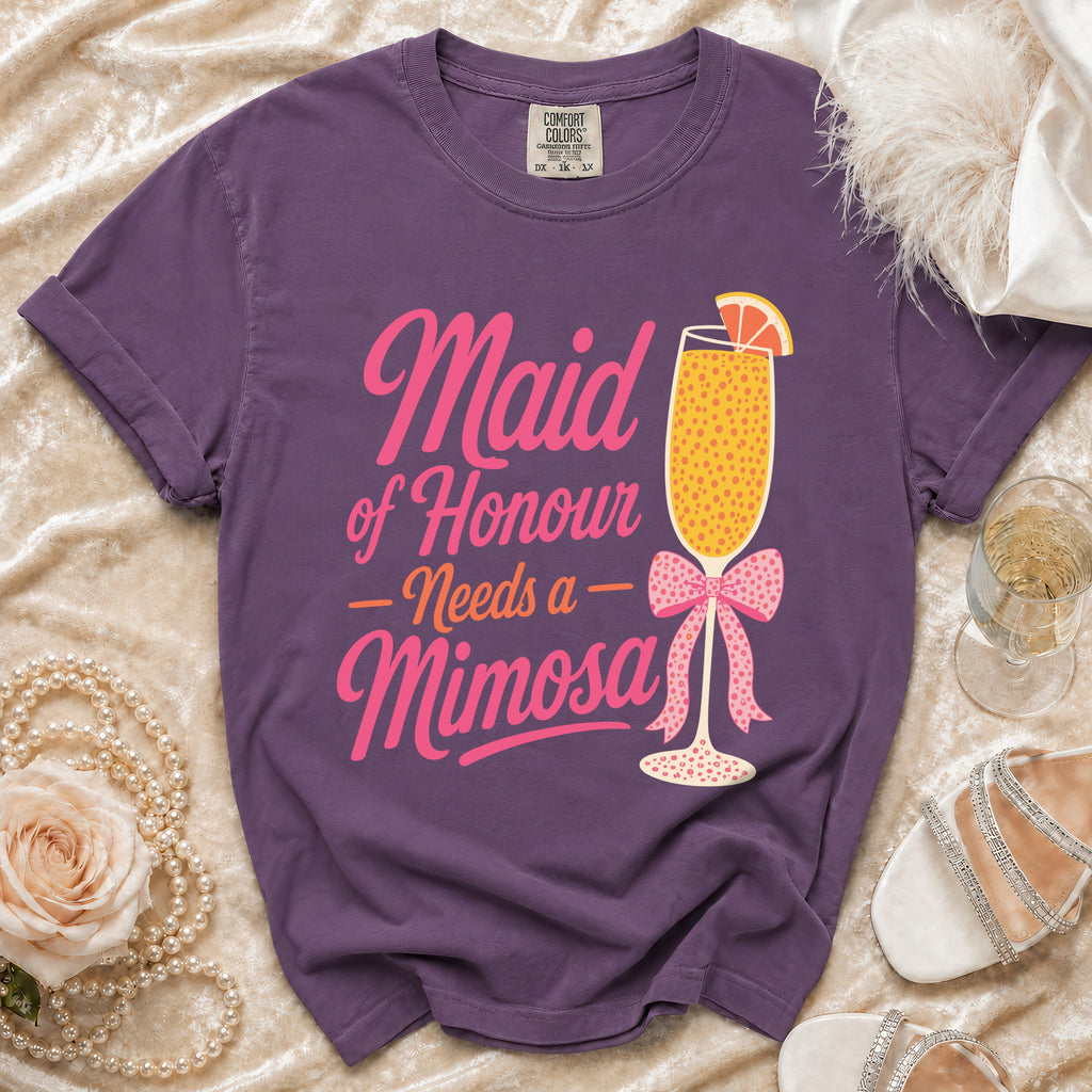 Purple t-shirt with "Maid of Honour Needs a Mimosa" text, mimosa glass, and bow graphic.