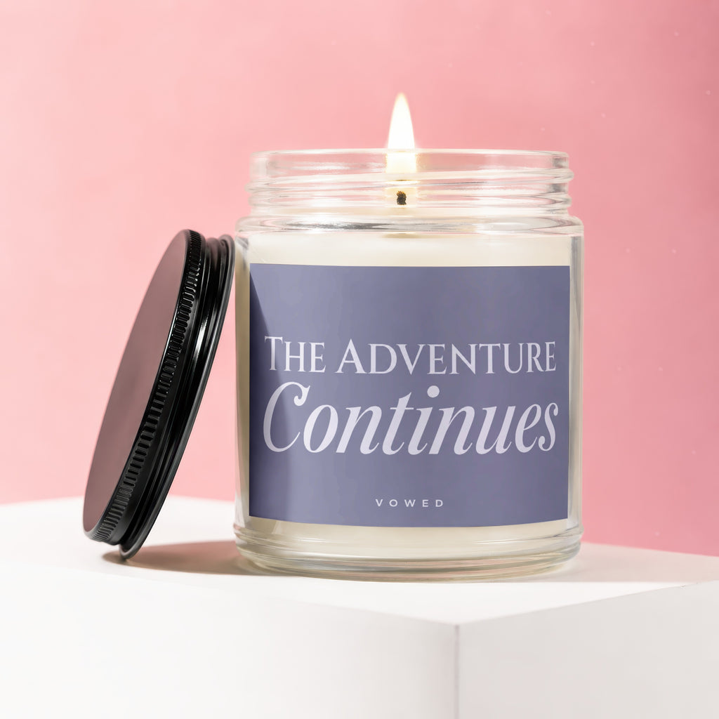Candle with lit wick on a white surface, pink background, "The adventure Continues" text.