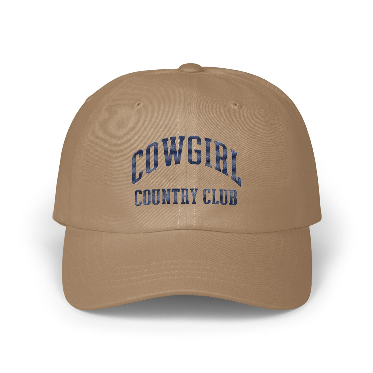 A tan baseball cap with dark blue embroidered text that reads Cowgirl Country Club.