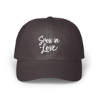 A dark gray baseball cap features white embroidered cursive text that reads Snow in Love.