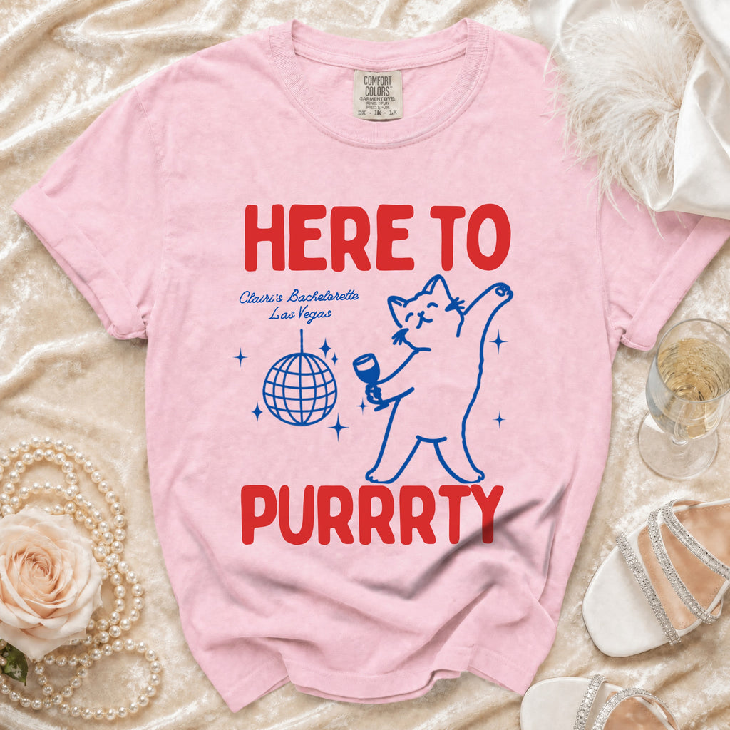Pink t-shirt with "HERE TO PURRRTY" text, a cat graphic, and "Claire's Bachelorette Las Vegas".