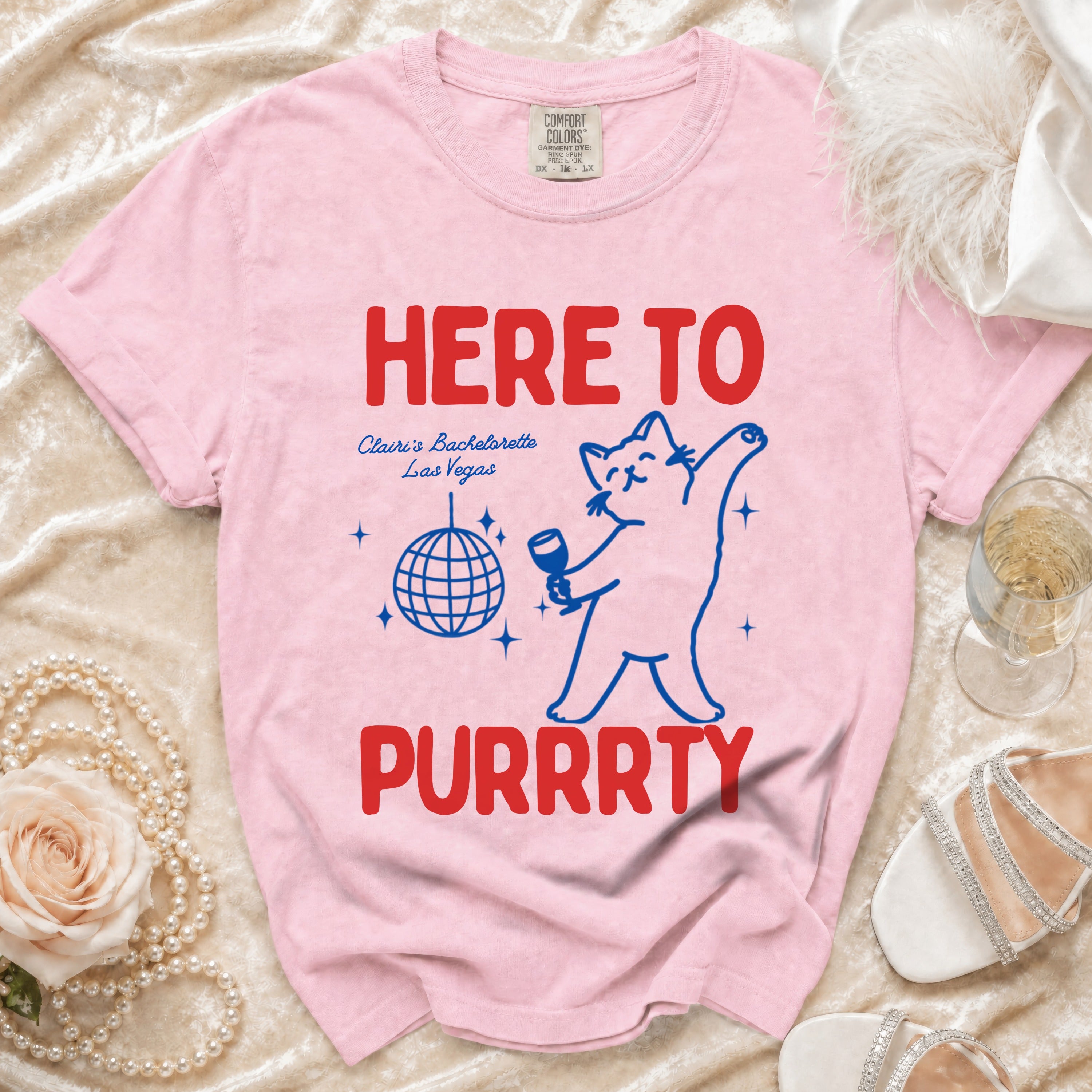 Pink t-shirt with "HERE TO PURRRTY" text, a cat graphic, and "Claire's Bachelorette Las Vegas".
