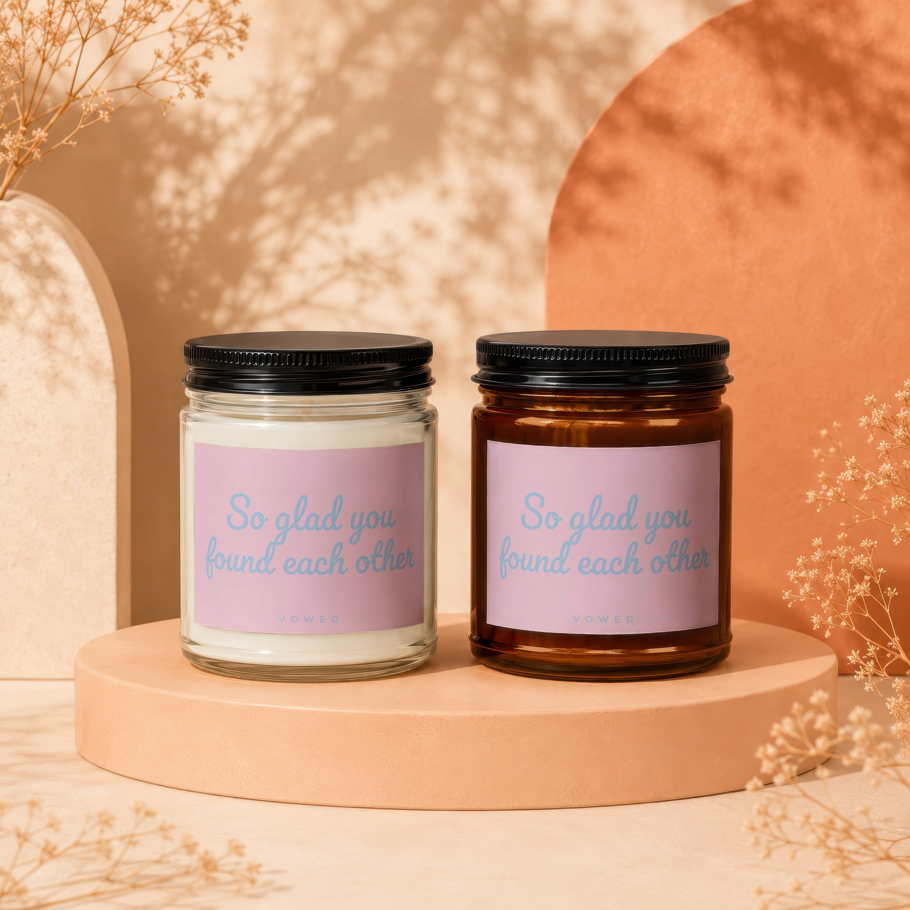 Two candles with pink labels reading "So glad you found each other" by Vowed.