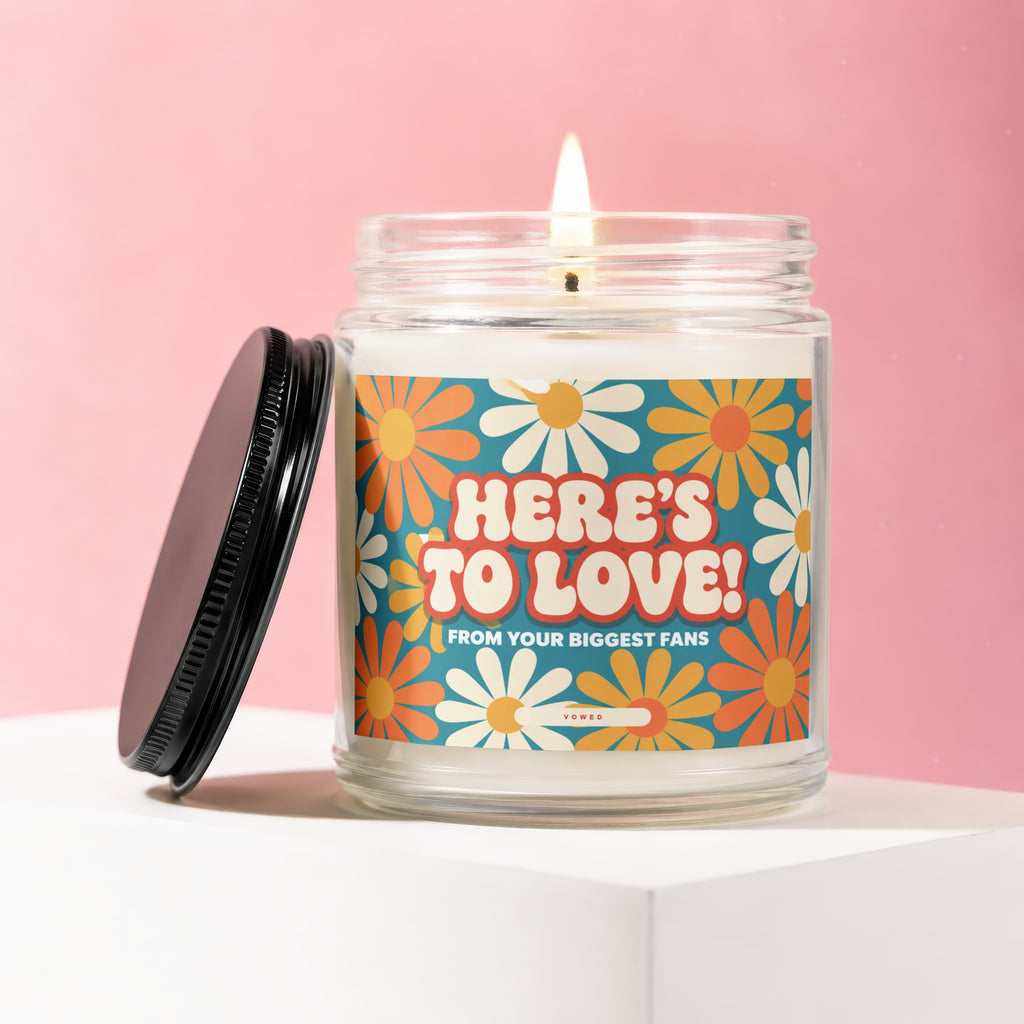 Candle with "HERE'S TO LOVE! FROM YOUR BIGGEST FANS" text and floral design.